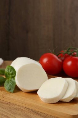 Lezzetli mozzarella, domates ve fesleğen ahşap masada, yakın plan.