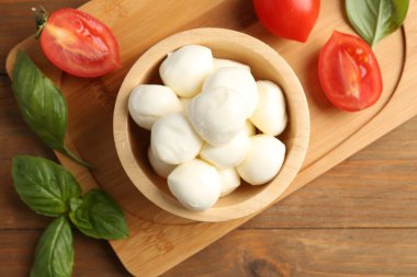 Lezzetli mozarella topları, domatesler ve fesleğenler ahşap masada, düz yatıyordu.