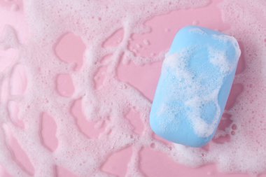 Pembe arka planda köpüklü sabun barı, üst manzara. Metin için boşluk