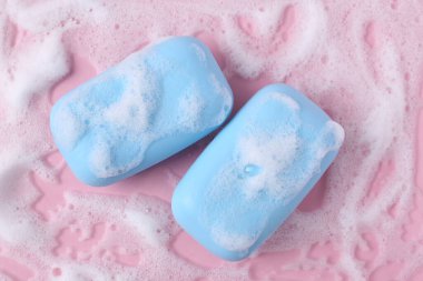 Pembe arka planda köpüklü sabun çubukları, düz yatış