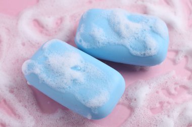 Pembe arka planda köpüklü sabun çubukları.