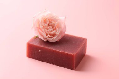 Sabun barı ve pembe arka planda güzel bir gül, yakın plan.