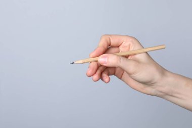 Gri arka planda grafit kalemi olan kadın, yakın plan. Metin için boşluk