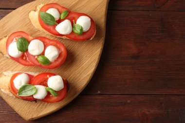 Mozarella peynirli, domatesli ve ahşap masadaki fesleğenli lezzetli sandviçler. Metin için boşluk