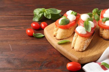 Mozarella peynirli lezzetli sandviçler, ahşap masada domates ve fesleğen, yakın plan. Metin için boşluk