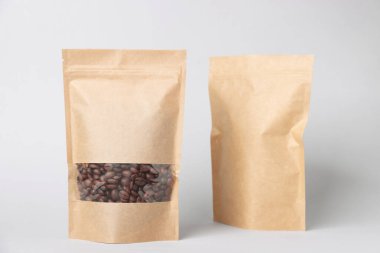 Beyaz arka planda kahve çekirdekleri olan fermuarlı stand-up torbaları. Tasarım için model