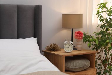 İçinde lamba, çalar saat ve yatağın yanında dekor olan komodin. İç tasarım