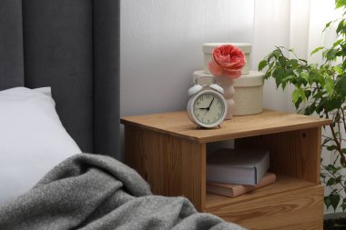 Alarm saati, kitaplar ve evin içinde yatağın yanındaki dekorun olduğu komodinin yanında. İç tasarım