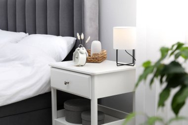 İçinde lamba, çalar saat ve yatağın yanındaki dekorun bulunduğu komodin.