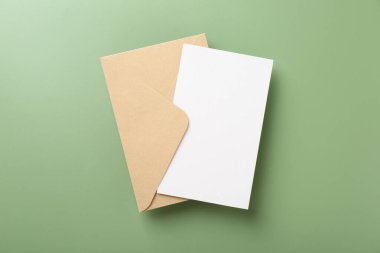 Açık yeşil arkaplanda boş davetiye ve zarf, üst görünüm