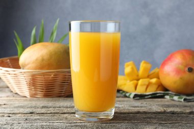 Bardakta lezzetli mango suyu ve ahşap masada taze meyve.