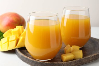 Bardakta lezzetli mango suyu ve beyaz masada taze meyve, yakın plan.