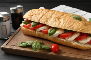 Mozarella peynirli, domatesli, fesleğenli, siyah ahşap masa, yakın plan.