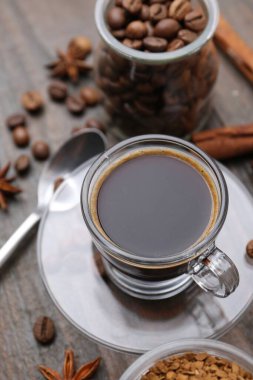 Bir fincan aromatik kahve, fasulye, hazır toz ve baharatlar ahşap masada, yakın plan.