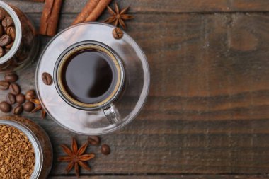 Bir fincan aromatik kahve, fasulye, hazır toz ve ahşap masa üzerindeki baharatlar, düz yatak. Metin için boşluk