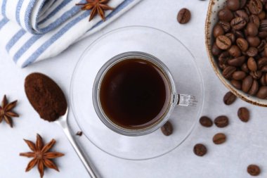 Bir fincan aromatik kahve, fasulye ve yıldız anason beyaz masada, düz yerde.