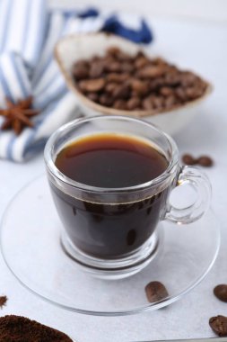 Bir fincan aromatik kahve, fasulye ve yıldız anason beyaz masada, yakın plan.
