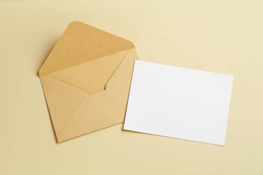 Bej arka planda boş davetiye ve zarf, düz yatış. Tasarım için boşluk