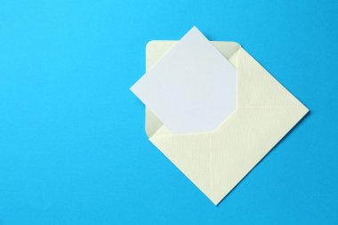 Açık mavi arka planda boş davetiye ve zarf, üst manzara. Metin için boşluk