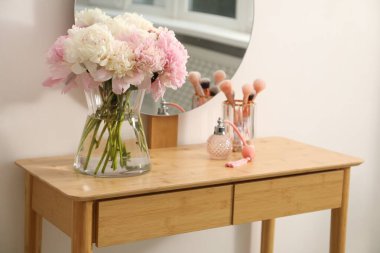 Vazodaki güzel şakayıklar, parfümler, fırçalar ve kapalı alandaki ahşap kibir aynaları.