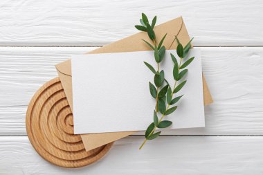 Boş davetiye kartı, zarf ve dallar beyaz ahşap masa, düz yatıyordu
