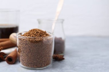 Granüle edilmiş hazır kahve ölçü kabı ve baharatlar gri desenli masa üzerinde, yakın plan. Metin için boşluk