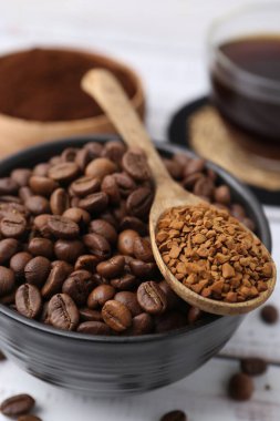 Kavrulmuş fasulye ve granüle edilmiş kahve beyaz ahşap masada, yakın plan.