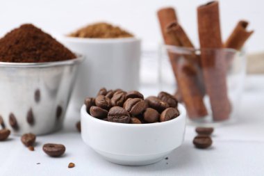 Kavrulmuş fasulye, farklı türde kahve ve tarçın çubukları ışık masasında, yakın plan.