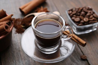 Kahve fincanda tazeleniyor ve tarçın çubuğu ahşap masada, yakın plan.