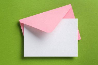 Yeşil arka planda boş davetiye ve zarf, üst manzara. Tasarım için boşluk