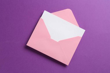 Mor arkaplandaki boş davet kartı ve zarf, üst görünüm