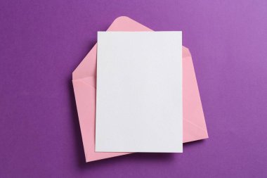 Mor arka planda boş davetiye ve zarf, üst manzara. Tasarım için boşluk