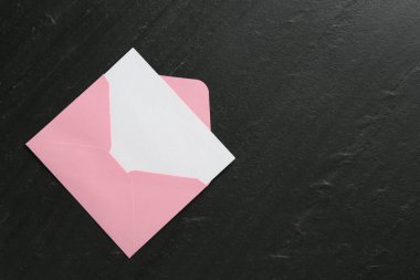 Boş davetiye kartı ve zarf siyah masanın üstünde, en üstte. Metin için boşluk