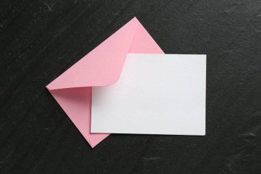 Boş davetiye kartı ve zarf siyah masanın üstünde, en üstte. Tasarım için boşluk