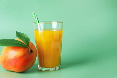 Bardakta lezzetli mango suyu ve yeşil arka planda taze meyve, metin için yer