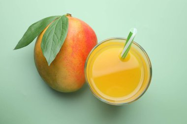 Bardakta lezzetli mango suyu ve yeşil arka planda taze meyve.
