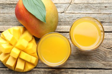 Bardakta lezzetli mango suyu ve ahşap masada taze meyveler.