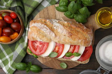 Peynirli, domatesli, ahşap masada fesleğenli lezzetli bir sandviç.