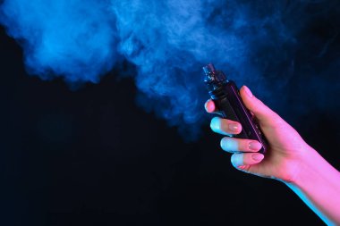 Siyah arka planda neon ışıklarda elektronik sigara içen bir kadın, yakın plan. Metin için boşluk