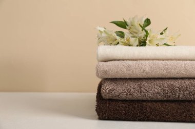 Beyaz masa üzerinde bej arka planda yumuşak havlu ve zambak yığını, yakın plan. Metin için boşluk