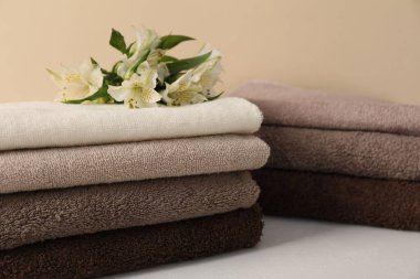 Beyaz masa üzerinde bej arka planda yumuşak havlu ve zambak yığını, yakın plan