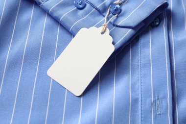 Açık mavi tişörtte karton etiket, üst görünümde