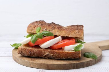 Mozarella peynirli, domatesli, fesleğenli, beyaz ahşap masa, yakın plan.