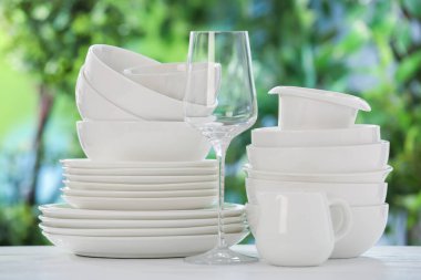 Bulanık yeşil arka planda beyaz masada farklı temiz tabaklar