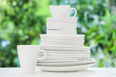 Bulanık yeşil arka planda beyaz masada farklı temiz tabaklar