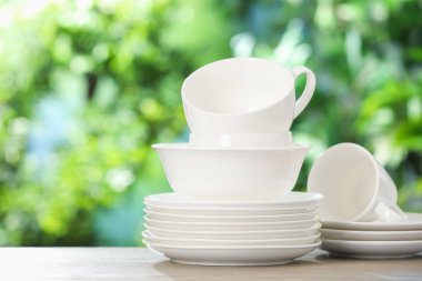 Ahşap masadaki farklı temiz tabaklar, bulanık yeşil arkaplan, metin için alan