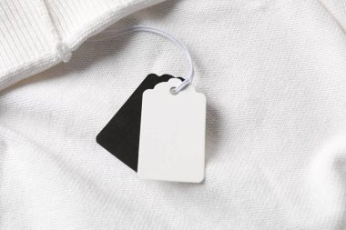 Beyaz giysinin üzerindeki karton etiketler, üst görünümde