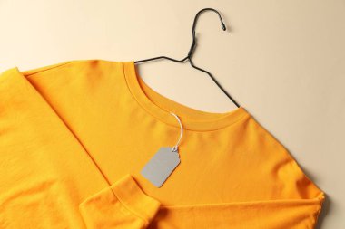 Bej arkaplanda etiketli turuncu giysi, üst görünüm