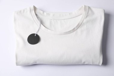 Beyaz arkaplanda etiketli tişört, üst görünüm