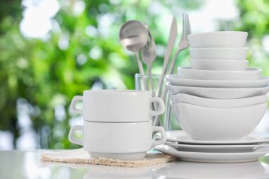 Bulanık yeşil arka planda beyaz masada farklı temiz tabaklar